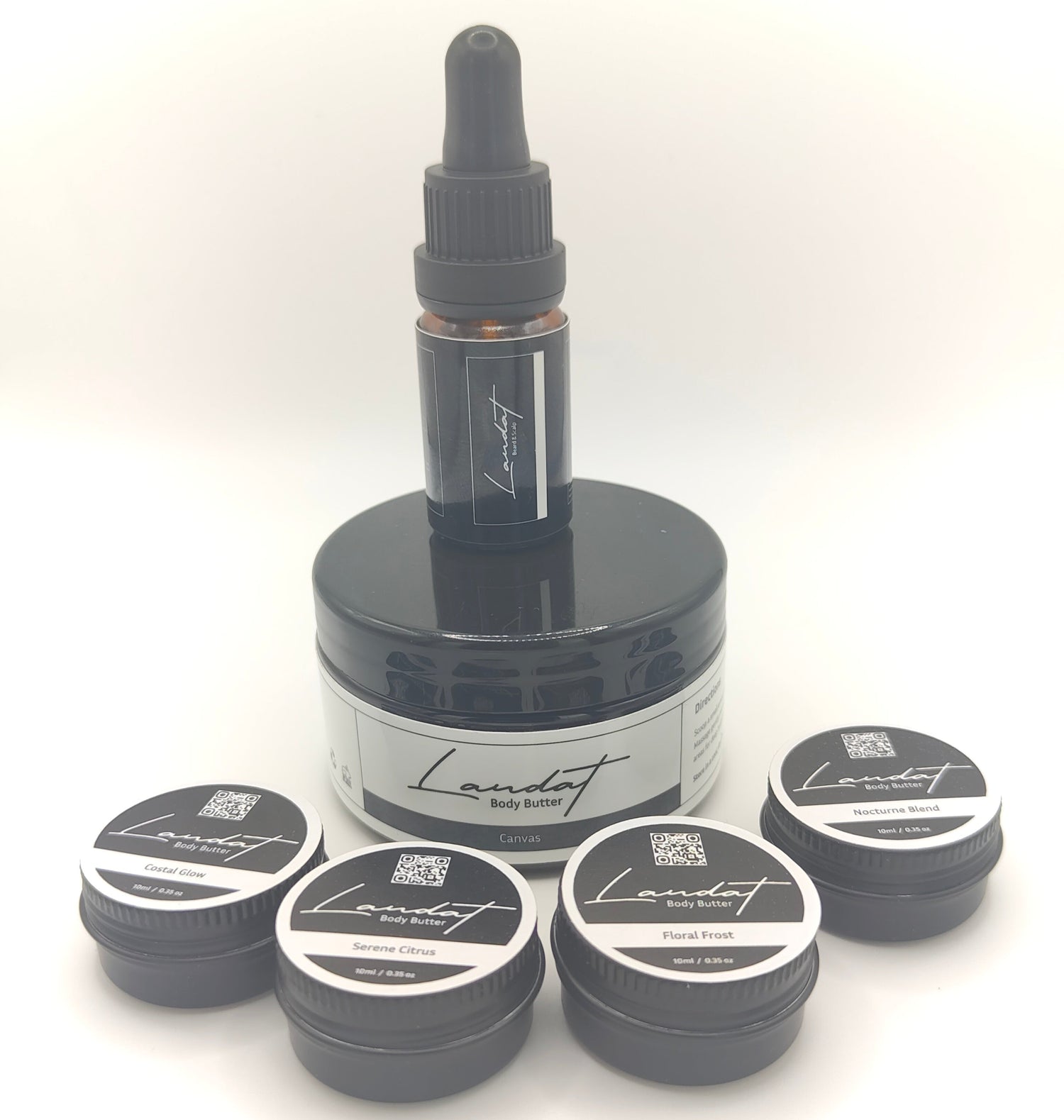 Collection of Laudat skincare products including a jar, dropper bottle, and small containers on a white background.